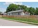 Street view of a home featuring a natural wood fence, grassy lawn, and mature trees against a blue sky at 802 N Tuxedo St, Indianapolis, IN 46201