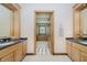 Bright bathroom with double sink and vanity, featuring wooden accents, and geometric patterned floors in the adjoining room at 815 Copperfield Ln, Danville, IN 46122