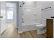 Bright bathroom featuring a tub-shower combo, light gray walls, and wood-look flooring at 8355 Fieldfare Way, Indianapolis, IN 46237