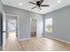 Spacious bedroom with wood-look floors, modern ceiling fan, and access to an ensuite bathroom at 8355 Fieldfare Way, Indianapolis, IN 46237