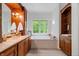Bright bathroom featuring wood cabinets, double sinks, and a large soaking tub at 9399 Irishmans Run Ln, Zionsville, IN 46077
