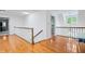 Well-lit upstairs hallway featuring hardwood floors and white railings with dark wood trim at 9399 Irishmans Run Ln, Zionsville, IN 46077