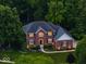 Beautiful two-story brick home with a well-manicured lawn and mature trees, lit windows at dusk at 9703 Fortune Dr, Fishers, IN 46037