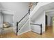 Staircase featuring hardwood floors, contrasting black and white railings, and views into adjoining living spaces at 9703 Fortune Dr, Fishers, IN 46037