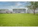 Large, green backyard with a view of the home's rear and neighboring houses under a partly cloudy sky at 10903 Greenleaf Dr, Indianapolis, IN 46229