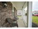 Inviting front porch with classic brickwork, white columns, seating, and a decorative front door at 10903 Greenleaf Dr, Indianapolis, IN 46229