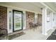 Inviting front porch with classic brickwork, white columns, seating, and a decorative front door at 10903 Greenleaf Dr, Indianapolis, IN 46229
