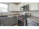 Close up on a stainless gas stove with red knobs and gray and white cabinets in modern kitchen at 10903 Greenleaf Dr, Indianapolis, IN 46229