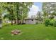 An expansive backyard with manicured lawn, fire pit, and mature trees at 1410 Lawrence Ave, Indianapolis, IN 46227
