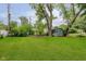 A spacious backyard with lush green grass, mature trees, and a storage shed at 1410 Lawrence Ave, Indianapolis, IN 46227