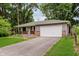 View of home's exterior with a driveway leading to an attached garage and a manicured front lawn at 1410 Lawrence Ave, Indianapolis, IN 46227