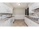 Functional kitchen featuring tile floors, white cabinets, stone counter tops, and modern appliances at 1410 Lawrence Ave, Indianapolis, IN 46227