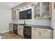 Modern bar area boasts light wood cabinets, black countertops, a marble backsplash, and dual wine refrigerators at 16244 Perrault Ct, Fishers, IN 46040