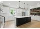 Modern kitchen features white cabinetry, stainless appliances, a black island, and wood look flooring at 16244 Perrault Ct, Fishers, IN 46040