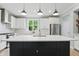 Modern kitchen with white cabinets, black island, stainless steel appliances and great lighting at 16244 Perrault Ct, Fishers, IN 46040