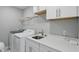 Laundry room featuring a sink, countertop, ample cabinets, and modern washer and dryer at 16244 Perrault Ct, Fishers, IN 46040