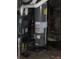 In a dark basement, a gray water heater sits next to the furnace at 1630 E 18Th St, Indianapolis, IN 46218