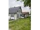 The back of a two-story white house reveals a small enclosed porch and a spacious grassy yard at 1630 E 18Th St, Indianapolis, IN 46218