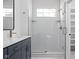 Beautiful bathroom with white tiled walls and shower, modern fixtures, and a vanity with a dark blue cabinet at 1655 Fernley Dr, Westfield, IN 46074