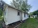 Side view of the home exterior featuring neutral siding, a window, green lawn, and trees at 1720 E Cornell Ave, Muncie, IN 47303