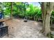Wide shot of backyard with mature trees, bench, storage for firewood, firepit, and wrought iron fence at 1898 Corniche Dr, Zionsville, IN 46077