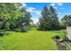 Backyard with lush green grass, mature trees, landscaping, mulch beds, and playground at 1898 Corniche Dr, Zionsville, IN 46077