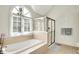 Bright bathroom features a soaking tub by a large window and a glass enclosed shower stall at 1898 Corniche Dr, Zionsville, IN 46077