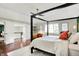 Bright main bedroom featuring a dark four-poster bed, hardwood floors, and stylish decor at 1898 Corniche Dr, Zionsville, IN 46077
