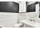 Stylish powder room showcases dark walls, decorative wainscoting, and a sleek round mirror at 1898 Corniche Dr, Zionsville, IN 46077