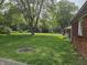 Chain link fence enclosing a sprawling backyard with mature trees and a fire pit at 2017 Schwier Ct, Indianapolis, IN 46229