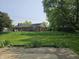 A grassy backyard with flowers, an old fire pit, and chain link fence, viewed from the patio at 2017 Schwier Ct, Indianapolis, IN 46229