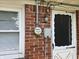 A close view of an exterior brick wall with a window, electric meter, and white door at 2017 Schwier Ct, Indianapolis, IN 46229