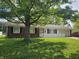Charming brick ranch-style home featuring a well-manicured lawn and mature shade tree in front yard at 2017 Schwier Ct, Indianapolis, IN 46229