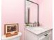 Powder room featuring pink walls, white vanity with granite countertop, decorative mirror and floral painting at 2433 Hideaway S Dr, Indianapolis, IN 46268