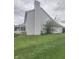 Angle view of a home's exterior with a large chimney, green grass, and back porch at 3714 Turfway Ct, Indianapolis, IN 46228