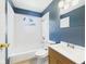 Bathroom featuring a tub and shower combo, toilet, and single sink vanity with blue walls at 4020 N Mitthoefer Rd, Indianapolis, IN 46235