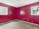 Bedroom featuring red walls, two windows, neutral carpet, and a modern ceiling light at 4020 N Mitthoefer Rd, Indianapolis, IN 46235