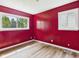 Bedroom featuring bright red walls, two windows, light hardwood floors, and a modern ceiling light at 4020 N Mitthoefer Rd, Indianapolis, IN 46235