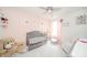 Beautiful Bedroom featuring a grey crib, plush carpet, pink accent wall and a soft white glider at 441 E Pine Ridge Dr, Westfield, IN 46074