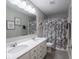 Bathroom featuring gray tile floors, double sink vanity, and shower tub with neutral shower curtain at 5684 Autumn Trl, Brownsburg, IN 46112