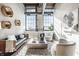Sun-drenched living room showcasing a leather sofa, modern decor, exposed ductwork, and ample natural light from large windows at 630 N College Ave # 409, Indianapolis, IN 46204