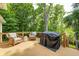 Outdoor deck with a grill and patio furniture surrounded by lush trees at 6940 Mockernut Ct, Plainfield, IN 46168