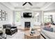 Bright living room features a fireplace, large windows with window seats, hardwood floors, and a ceiling fan at 6940 Mockernut Ct, Plainfield, IN 46168