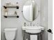 Stylish powder room featuring a pedestal sink, round mirror, and wall decor at 6940 Mockernut Ct, Plainfield, IN 46168