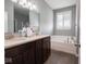 Bathroom with a double sink vanity, garden tub under a window, and wood-look flooring at 7329 Birch Leaf Dr, Indianapolis, IN 46259