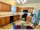 Open kitchen featuring warm wood cabinetry, stainless steel appliances, and a glass-top dining table at 7611 Cloudy Ct, Camby, IN 46113