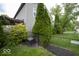 View of home exterior featuring manicured evergreens and a black chain-link fence at 7657 Wheatgrass Ln, Noblesville, IN 46062