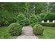 Serene backyard walkway surrounded by lush greenery, leading to a tranquil seating area at 8436 N Meridian St, Indianapolis, IN 46260