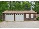 Detached two-car garage featuring carriage doors and charming wood siding, nestled amongst lush greenery at 8436 N Meridian St, Indianapolis, IN 46260