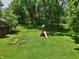 Lush backyard featuring green lawn, mature trees and a playset at 9014 Holliday Dr, Indianapolis, IN 46260